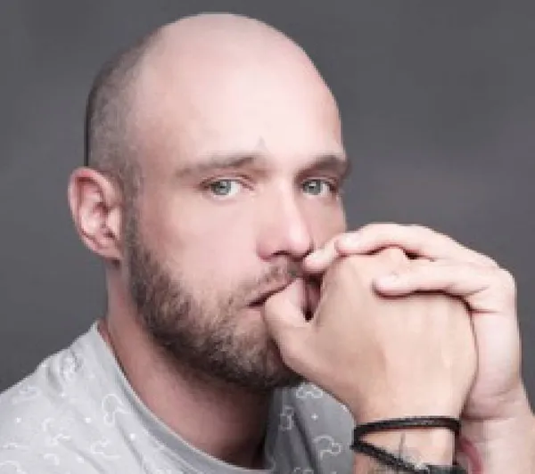 Zoltan, chin on his clasped hands, against a grey backdrop